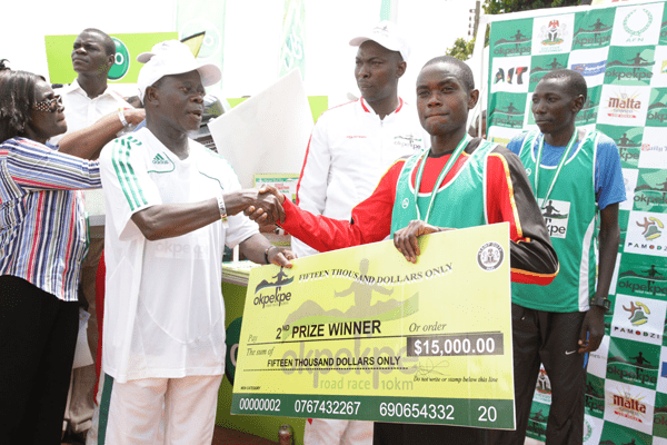 Edo Governor Adams Oshiomhole presents a cheque to Timothy Toroitich from Uganda, 2nd prize winner with time of 29 mins, 44 seconds at the Okpekpe Road Race 10km.