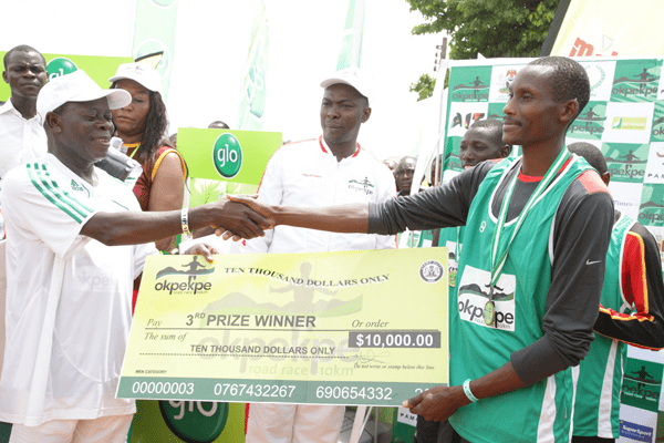 Edo Governor Adams Oshiomhole presents a cheque to Yusuf Biwott, 3rd prize winner with time of 29 mins 50 seconds at the Okpekpe Road Race 10km.